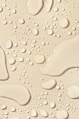 Cosmetic moisturizing liquid drops on nude skin color beige pastel background. Toner or lotion....