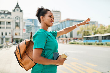 Nurse iwalking down the street  and using a mobile phone outside  waiting for transportation or...
