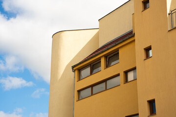 In Bulgaria, a building features modern architecture with a mix of shapes and colors. The yellow structure contrasts with a clear blue sky, creating a notable urban scene for travelers