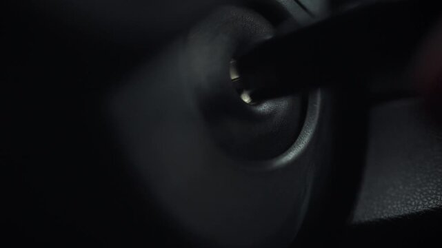 The driver's hand grasps the car key, carefully turning it in the ignition switch to initiate engine startup, a precise motion that activates the vehicle's mechanical systems