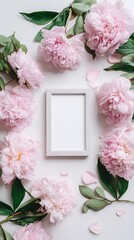 Top view of light pink peonies framing a blank white picture frame