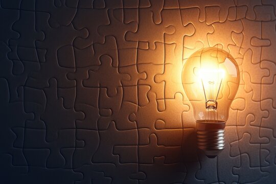 Light bulb glowing on dark puzzle background symbolizing idea and solution concept with warm light illuminating surrounding pieces in creative and inspiring way