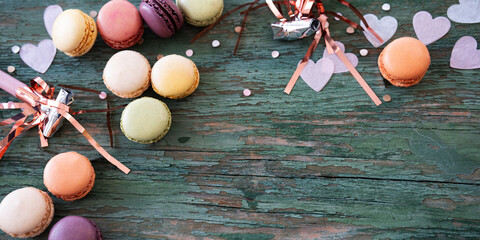 Birthday celebration with delicious macarons surrounded by pink confetti hearts on green shabby...