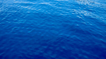 Obraz premium Blue water surface. Blue water background. Deep blue ocean surface with gentle ripples. Calm water patterns form a abstract background.