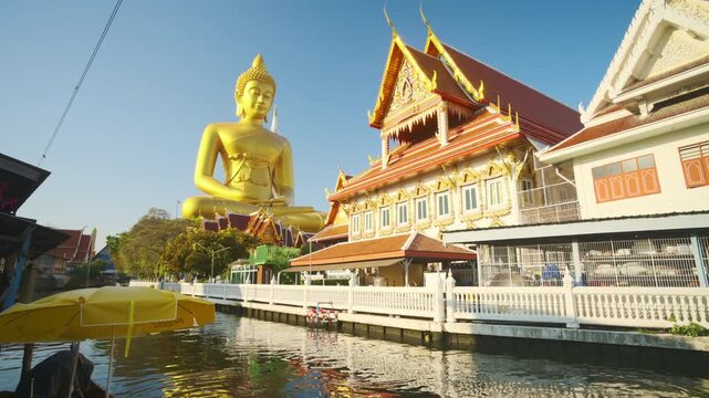 Golden big buddha statue riverside Wat Paknam with wooden boat sightseeing travel in Bangkok Thailand
