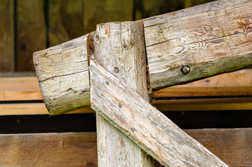 A wooden frame displays its joints and textures. The rough surface shows signs of age and wear, typical in a rustic environment. Sunlight highlights the details of the wood.