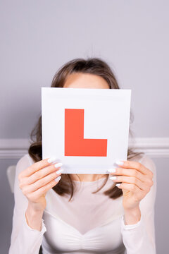 Woman learner driver holding L plate preparing for driving test. Personal goal, focus on L plate