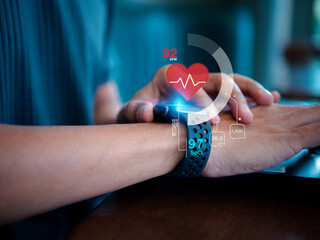 Close-up of a male hand wearing a smartwatch displaying heart rate data on a futuristic dark background, representing digital health monitoring, wearable technology, and modern healthcare innovation.