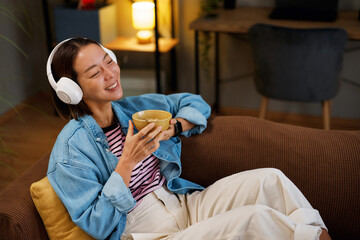 Young woman relaxing at home enjoying music and snack