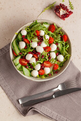 Vegetable salad with cheese and pomegranate grains on a light background. Top view