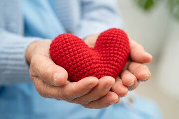 Asian elder senior woman patient holding red heart in hospital.
