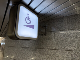 Wall mounted sign indicating wheelchair ramp in hallway. Wheelchair accessible area with special ramp for people with limited mobility. Accessible area, assistance to people with disabilities