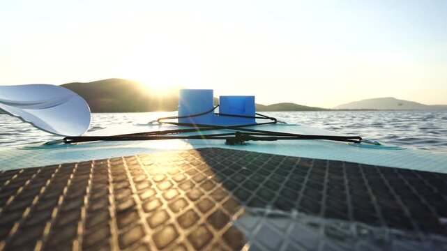 Blue turquoise SUP board in wavy open water. Stand Up Paddle board activity has water sport in the dam during hill in twilight sun. Rowing boat in nature.