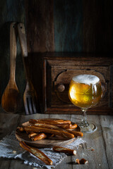 A glass of light beer and crackers on a rustic table