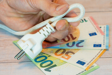 Power cord in hand and euro money concept for energy cost and efficiency saving