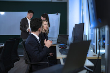 Two software developers engage in pair programming or a code review, discussing a complex function. In the background, team members map out the system architecture on a whiteboard for the next sprint.