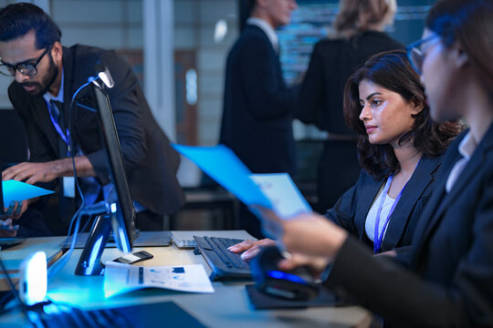 A team of financial analysts works through the night in a fast-paced firm, processing market data, reviewing performance reports, and executing trades to manage investment portfolios. - Powered by Adobe