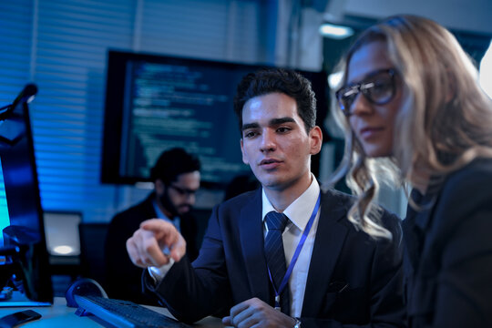 Two software developers smile with satisfaction during a pair programming session, as one points to a successfully executed block of code after solving a complex programming problem.