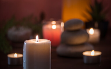 background image composed of lit candles, stones, and plants in the dark.