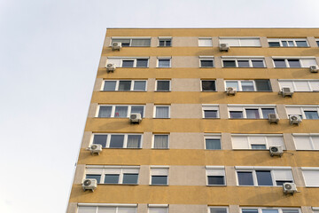 Building with multiple windows and air conditioning units in urban area during daytime