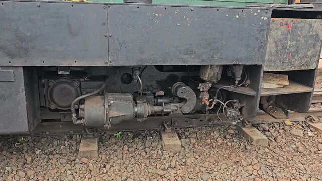 Matheran, Maharashtra, India &ndash; Close-up view of a narrow-gauge train undercarriage resting on tracks, showing mechanical details of heritage rail transport in the hills.