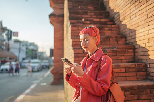 Traveler girl using mobile phone on street in city Fashion gen z asian woman 
Technology connection outdoor communication generation z modern lifestyle