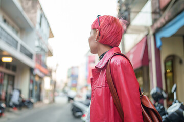 Gen z girl leather fashion with punk Asian woman tourist of local city Southeast Asia travel trendy pink hairstyle young female punk traveler walking around in town