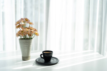 Black coffee cup and Chrysanthemum flowers vase on white table