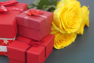 Fototapeta premium Yellow roses bouquet and gift boxes on blue background. Birthday and holidays concept.