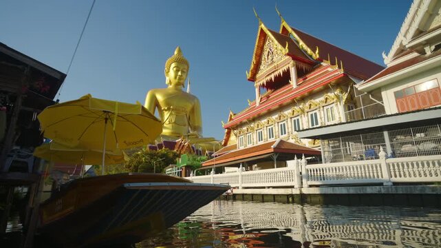 Giant golden buddha statue at the Wat Paknam Phasi Charoen temple with wooden boat famous buddhist and the peaceful beauty in Bangkok, Thailand
