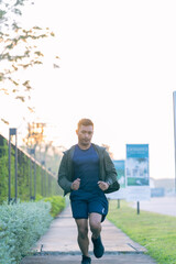 A young Asian man is jogging outdoors in a park in the morning. The concept of exercise for health is depicted.