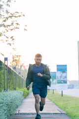 A young Asian man is jogging outdoors in a park in the morning. The concept of exercise for health is depicted.
