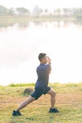 A young man in a T-shirt and shorts is stretching, with the sunlight shining in the background, creating a pre-workout training atmosphere.