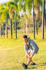 A young man in a T-shirt and shorts is stretching, with the sunlight shining in the background, creating a pre-workout training atmosphere.