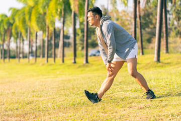 A young man in a T-shirt and shorts is stretching, with the sunlight shining in the background, creating a pre-workout training atmosphere.