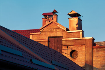 Brick industrial building rooftop with chimneys illuminated by warm evening sunlight