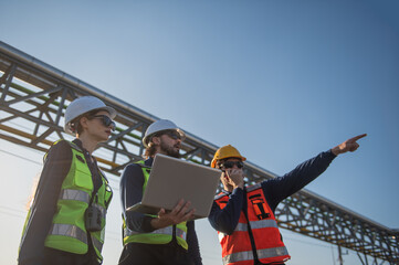 Industrial Engineers Inspecting Construction Site with Laptop, engineering teamwork, industrial inspection, project management and modern construction technology.