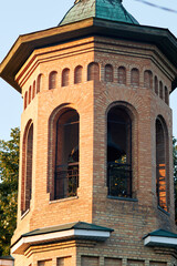 Historic brick bell tower with arched windows illuminated by warm golden hour light