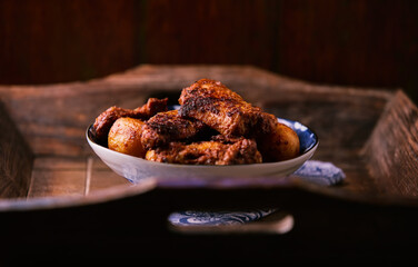 Fried chicken wings with potatoes on a rustic background. Soft focus.