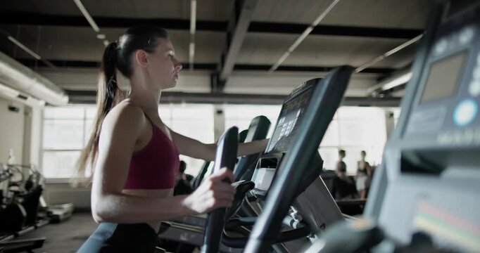 Young beautiful woman in sportswear doing cardio workout and exercises on stepper machine in the gym