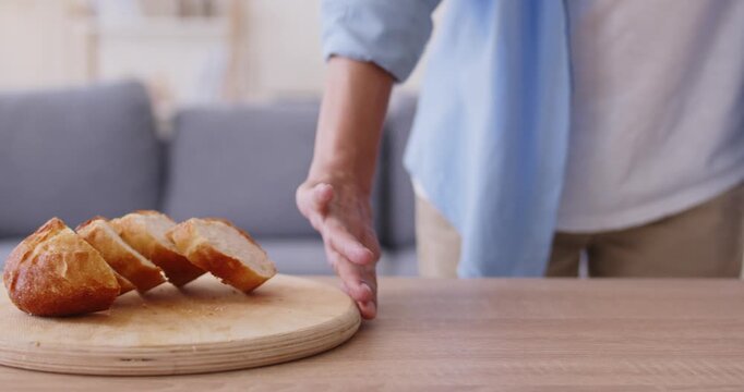 Hand of woman refusing grain bread eating, pushing wooden board with loaf slices away on table due to stomach pain and gluten intolerance. Diet choice of person with celiac disease, gut discomfort