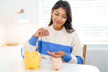 Woman counts coins while sitting at a table with piggy banks in a well-lit room during daytime