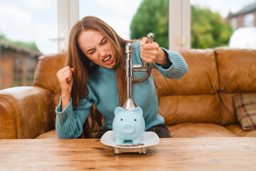 Person uses heavy object to break piggy bank at home while feeling frustrated about savings