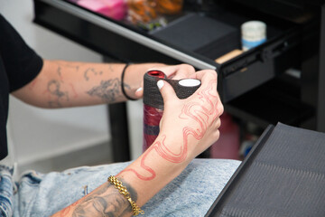 The young professional tattoo artist is attaching the grip tape to the tattoo machine to make it more comfortable and prevent slipping.