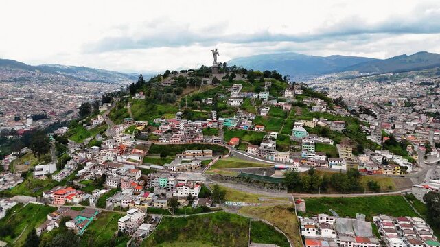 Aerial drone footage of El Panecillo hill featuring the iconic Virgin of Quito statue overlooking the city of Quito, Ecuador. Important cultural and religious landmark with panoramic views of the capi