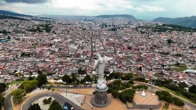 Aerial drone footage of El Panecillo hill featuring the iconic Virgin of Quito statue overlooking the city of Quito, Ecuador. Important cultural and religious landmark with panoramic views of the capi