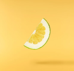 Fresh ripe green sweetie falling in the air isolated on yellow background
