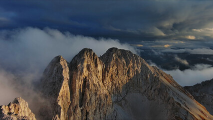 Amazing rocky mountains in clouds at sunset