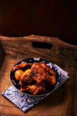 Fried chicken wings with potatoes on a rustic background
