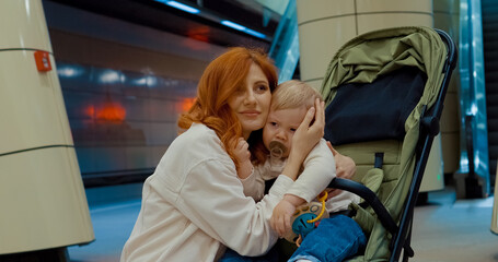 Mother hugs her baby at subway station platform during travel time